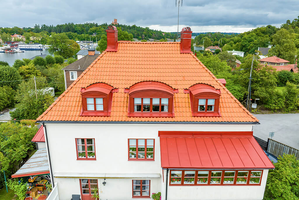Vit villa i Solna med röda takpannor och röda plåtdetaljer