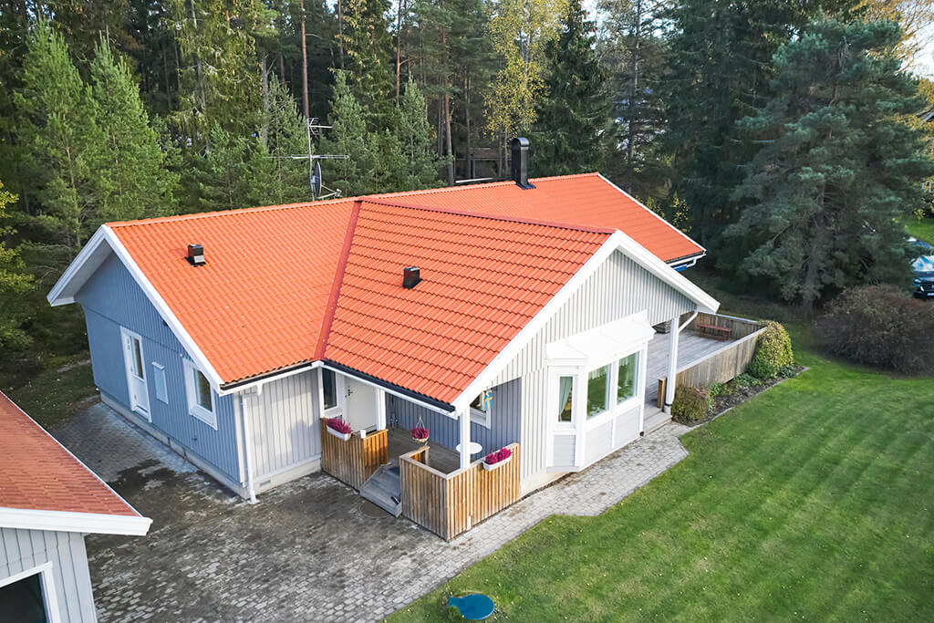 Ljusgrå villa med nytt tak av orangea takpannor