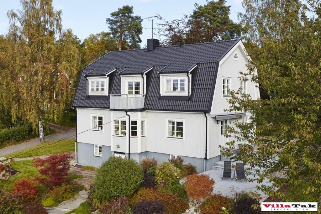 Vit villa med mansardtak av svarta takpannor