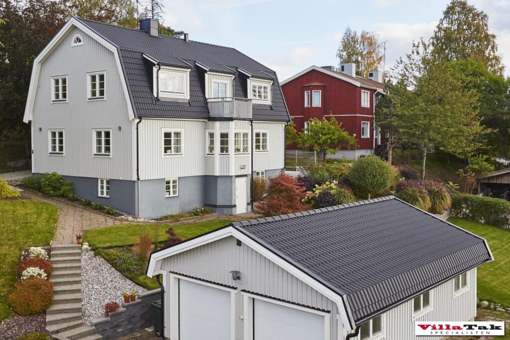 Vit villa med mansardtak av svarta takpannor